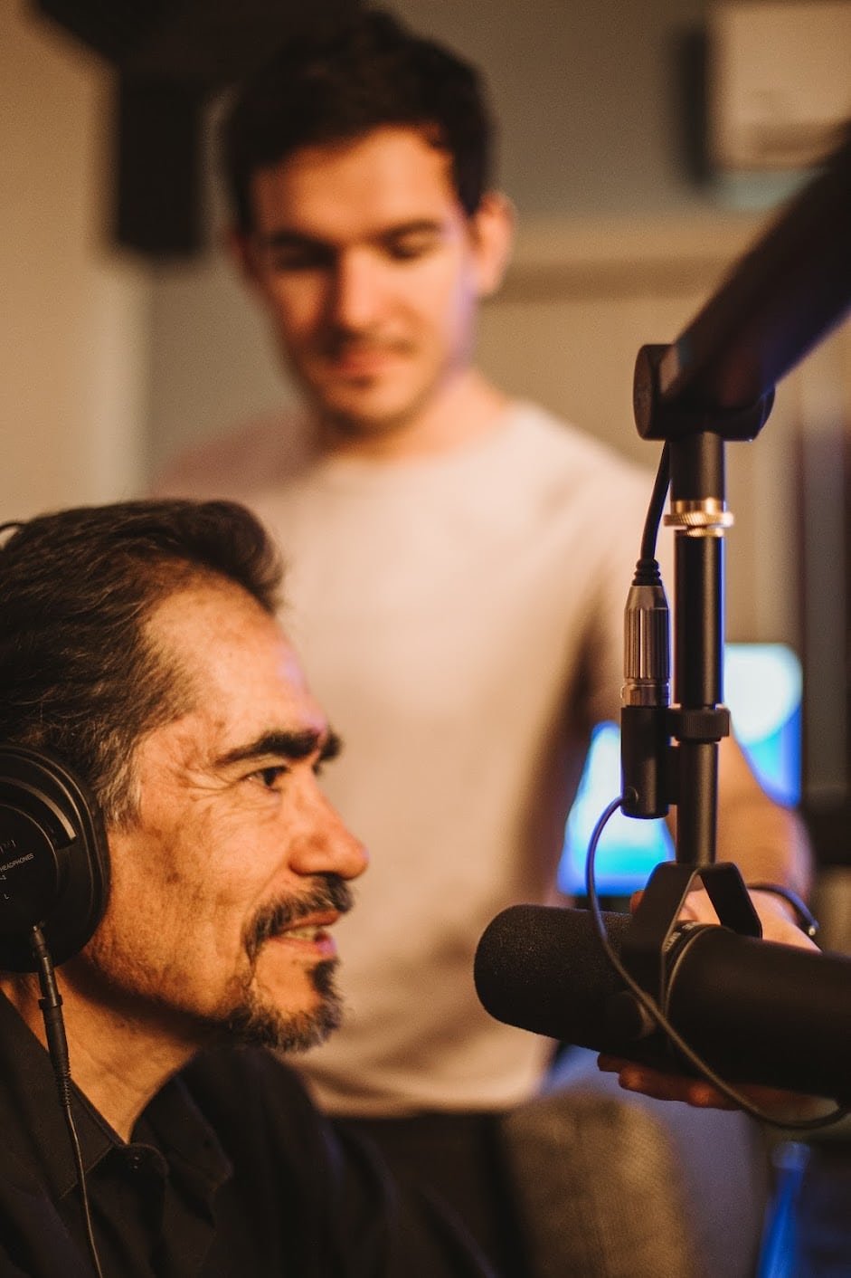Instructor enseñando grabación de podcast en estudio profesional con micrófono y audífonos