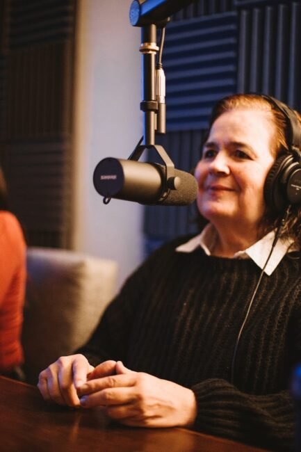 Mujer grabando podcast corporativo en estudio profesional con micrófono Shure SM7B durante sesión de producción en Soonus Guadalajara.