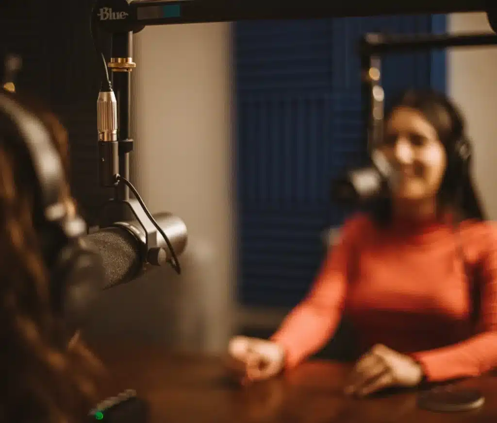 Dos mujeres grabando un podcast en estudio profesional con micrófonos de condensador.