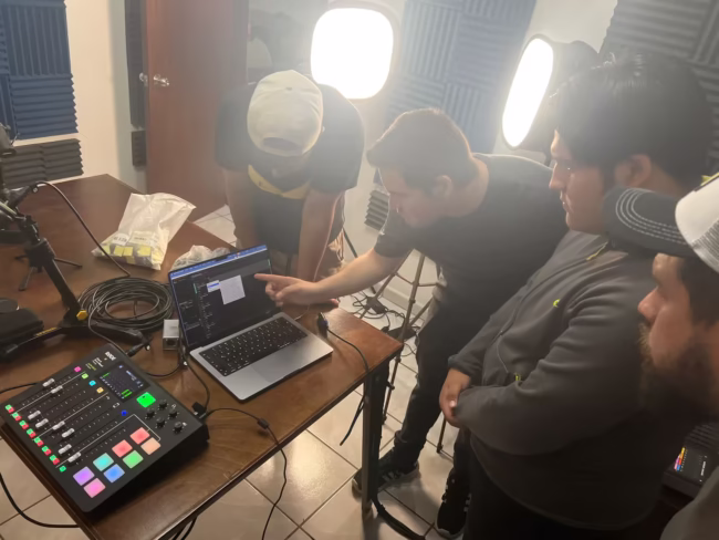 Participantes del curso de podcasting profesional de Soonus en sesión práctica, usando mezcladora profesional y laptop en estudio de grabación.